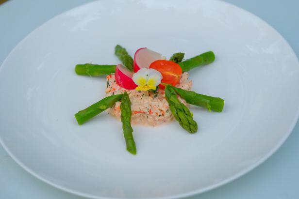 Ein Teller mit Krabbensalat, Spargel, Radieschen, Tomate und einer essbaren Blüte.