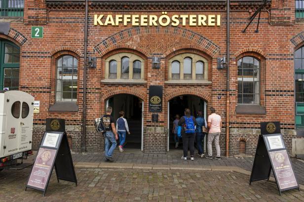 Mehrere Personen betreten die Speicherstadt Kaffeerösterei in einem Backsteingebäude.