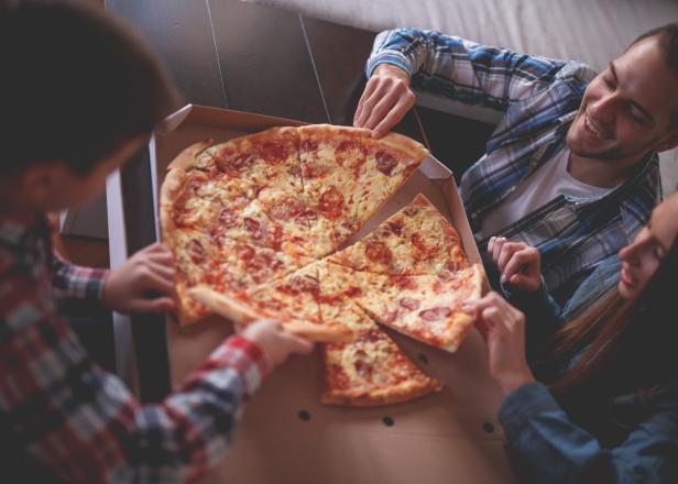 Freunde teilen sich zu Hause eine Pizza mit Salami.