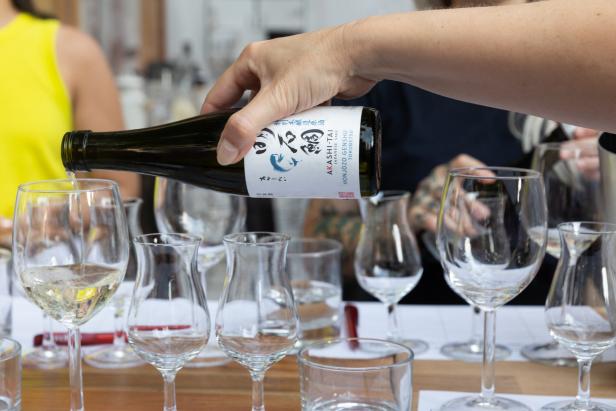 Eine Hand schenkt Akashi-Tai Sake in ein Glas ein.
