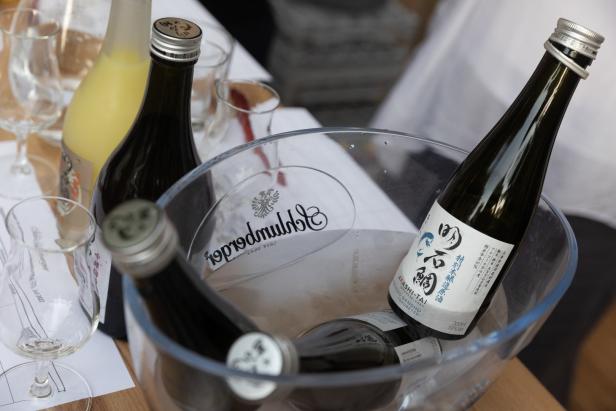 Mehrere Flaschen Akashi-Tai Sake in einem durchsichtigen Behälter mit Eis.