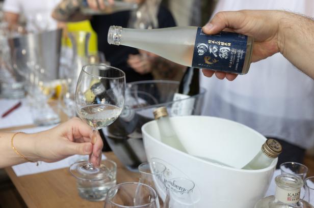 Eine Person gießt japanischen Sake der Marke „Akashi-Tai“ in ein Weinglas.