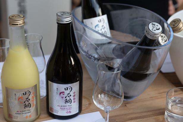 Mehrere Flaschen Akashi-Tai Sake und Ume-Likör stehen auf einem Tisch.
