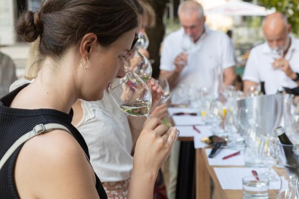 Eine Frau riecht an einem Glas Weißwein bei einer Weinprobe.