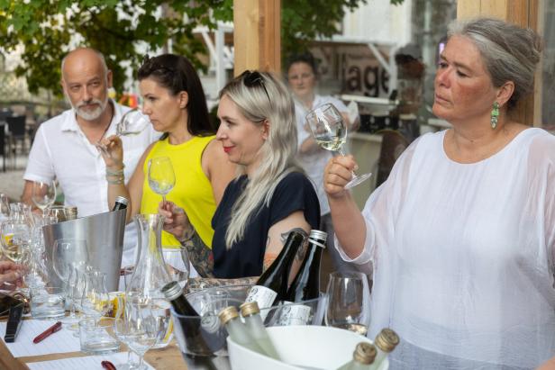 Eine Gruppe von Personen verkostet Wein bei einer Weinprobe im Freien.