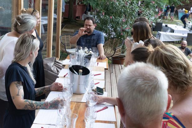 Eine Gruppe von Leuten nimmt an einer Weinprobe im Freien teil.
