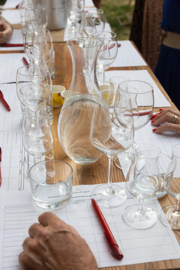 Ein Tisch mit Gläsern, einer Karaffe Wasser und Verkostungsnotizen bei einer Weinprobe.