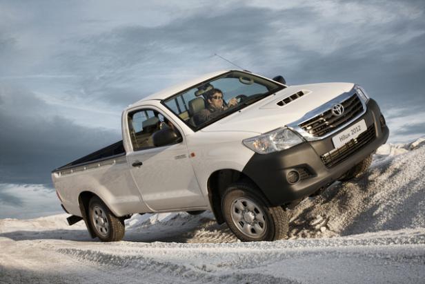 Ein weißer Toyota Hilux 2012 fährt auf einer unebenen, weißen Oberfläche.