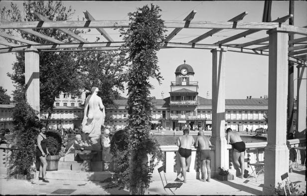 Historisches Schwarzweißfoto eines Freibads mit Badegästen und einer Statue.