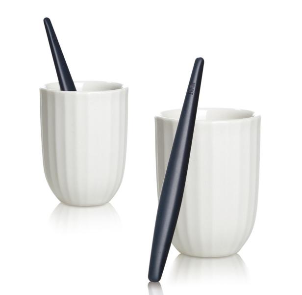 Zwei weiße Tassen mit einem blauen Rührstäbchen, eines davon in einer Tasse.