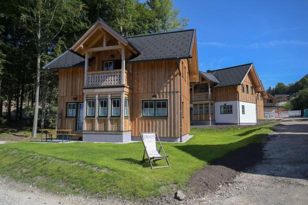 Ein modernes Holzhaus mit Balkon und einem Liegestuhl im Garten.