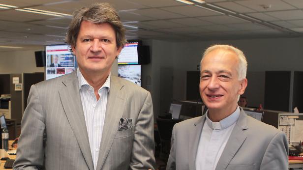 KURIER-Herausgeber Helmut Brandstätter und Caritas-Chef Michael Landau im Newsroom des KURIER Zwei Männer in Anzügen stehen in einem Büro.