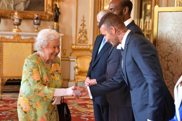 Königin Elizabeth II. schüttelt David Beckham die Hand.
