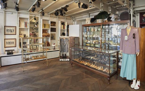 Ein Innenraum eines Geschäfts mit Kleidung, Accessoires und Dekorationsgegenständen in Vitrinen und Regalen.