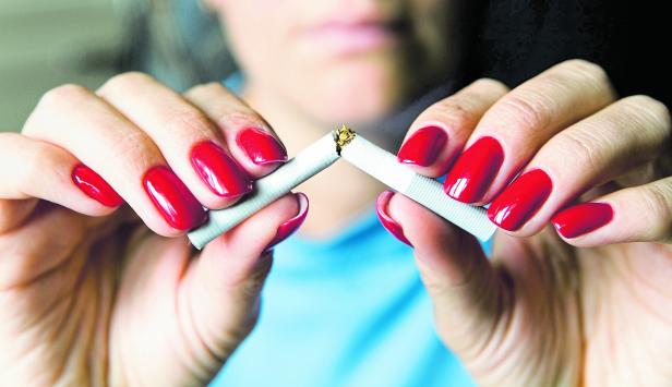 A girl with a beautiful manicure breaks a cigarette.