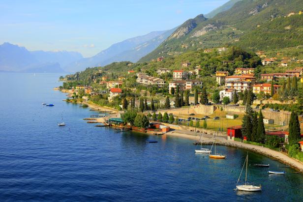 Blick auf eine Küstenstadt am Gardasee, umgeben von Bergen.
