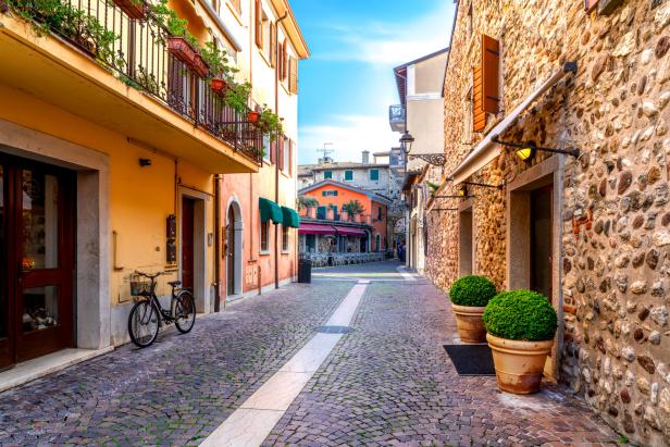 Eine malerische Gasse in einer italienischen Stadt mit Kopfsteinpflaster und bunten Häusern.