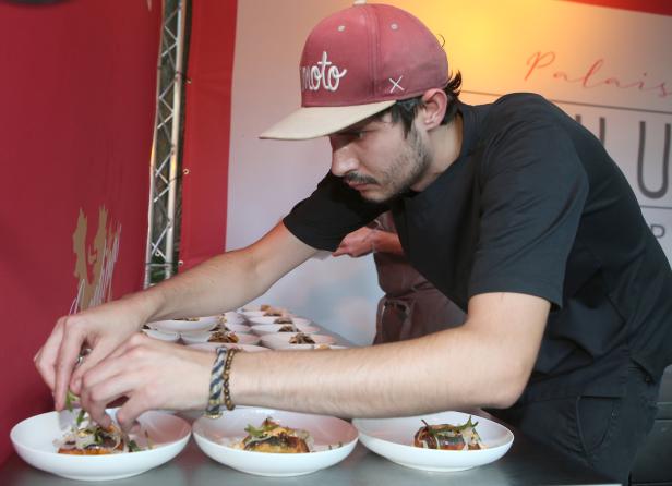 Ein Koch garniert Teller mit Speisen in einer Restaurantküche.