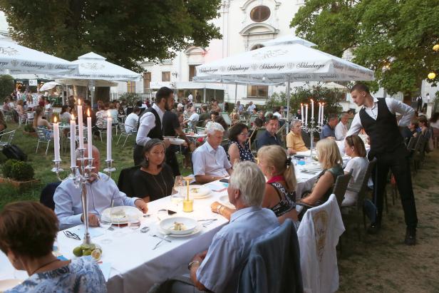 Gäste speisen im Freien unter Sonnenschirmen und Kerzenlicht.