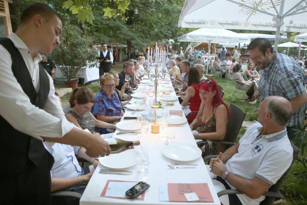 Ein Kellner schenkt Wein bei einem festlichen Abendessen im Freien ein.