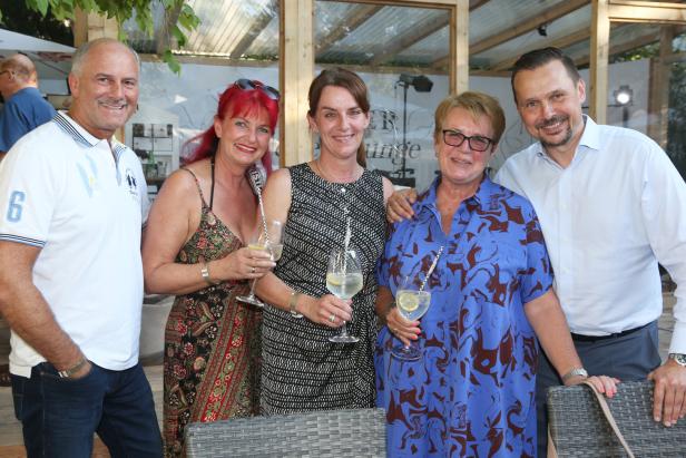 Eine Gruppe von fünf Personen posiert mit Getränken für ein Foto.
