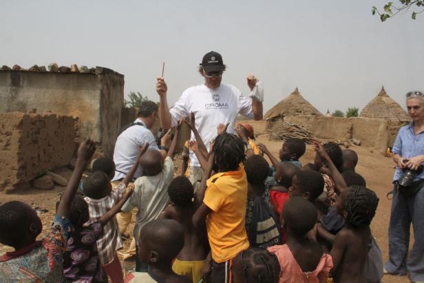 Eine Gruppe Kinder umringt einen Mann mit einem T-Shirt der Organisation CROMA.