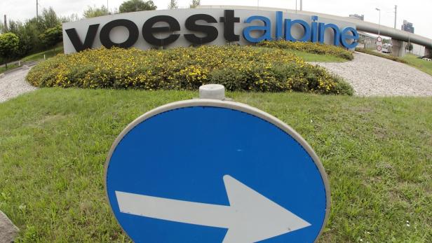 Ein blaues Richtungsschild vor dem Schriftzug „voestalpine“.