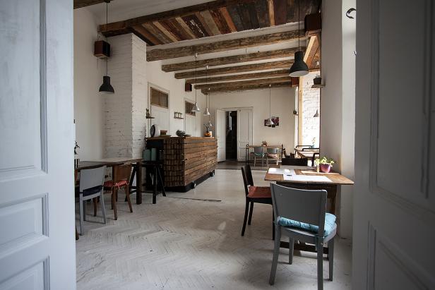 Ein Blick durch eine offene Tür in ein helles Café mit Holzbalkendecke.