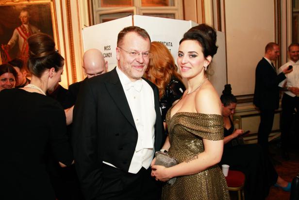 Ein Mann im Smoking und eine Frau im goldenen Kleid posieren für ein Foto.