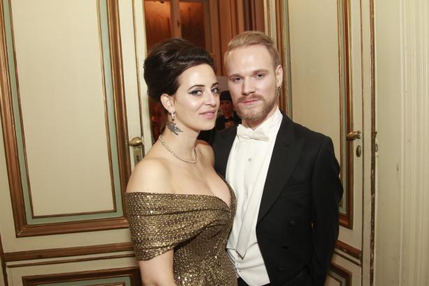 Eine Frau in einem goldenen Kleid und ein Mann im Smoking posieren für ein Foto.