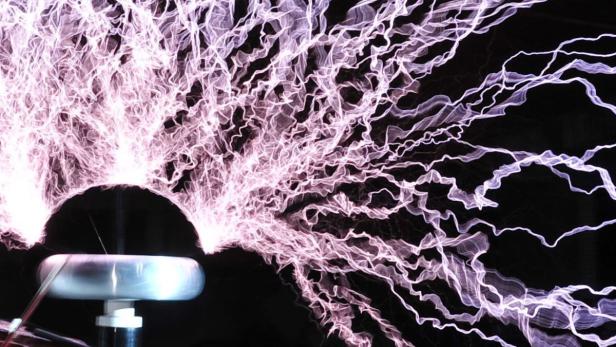 Ein Tesla-Transformator erzeugt violette Blitze in einer dunklen Umgebung.