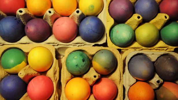 Mehrfarbige Ostereier liegen in Eierkartons.