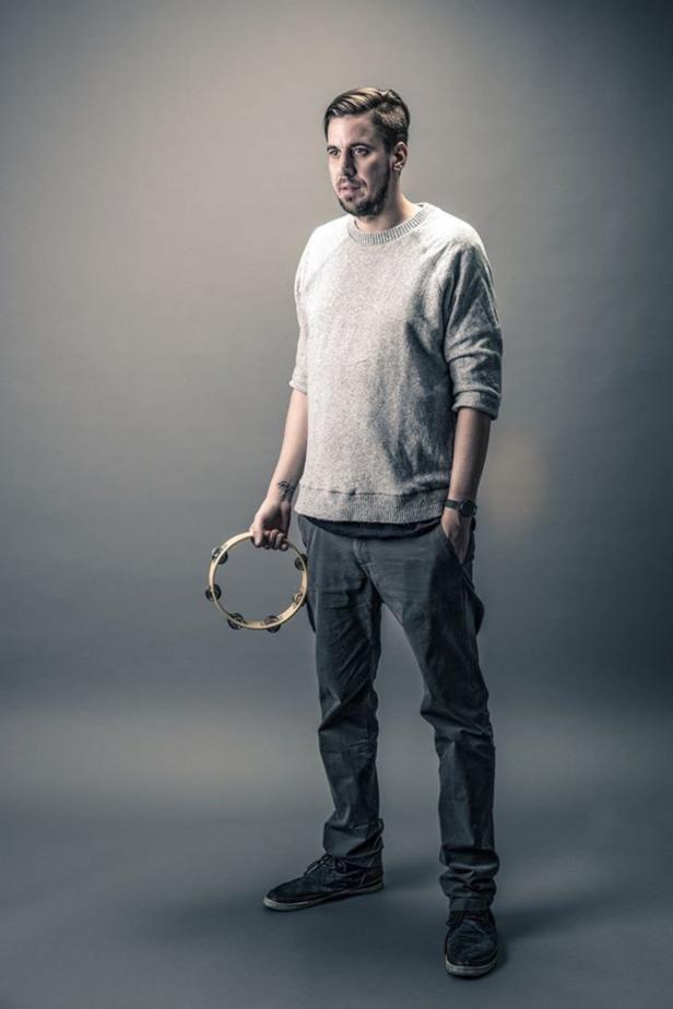 Oliver Koletzki… Ein Mann mit Bart hält ein Tamburin in der Hand.