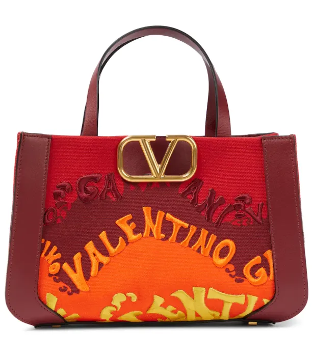 Eine rote Valentino-Tasche mit dem Schriftzug „Valentino“ in bunten Farben und goldenem Logo.