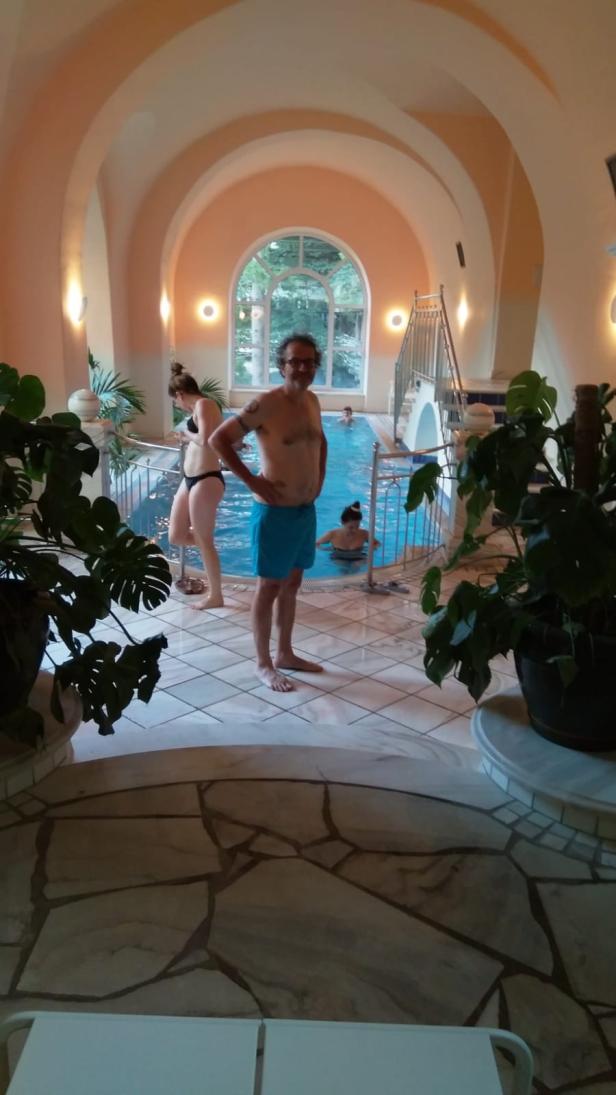 Menschen entspannen sich in einem Hallenbad mit gewölbter Decke.