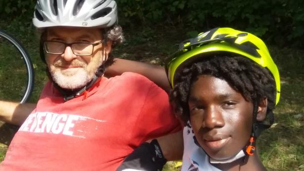 Zwei Personen mit Fahrradhelmen posieren für ein Foto im Freien.