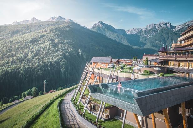 Eine Frau schwimmt in einem Pool mit Blick auf eine grüne Berglandschaft.