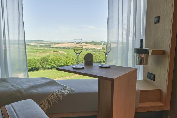 Zwei Weingläser stehen auf einem Tisch mit Blick auf eine grüne Landschaft.