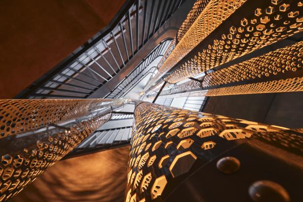 Eine Wendeltreppe mit einem Muster aus sechseckigen Aussparungen, von unten fotografiert.
