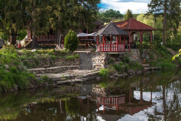 Ein roter Pavillon und ein gestreiftes Haus spiegeln sich im Wasser.