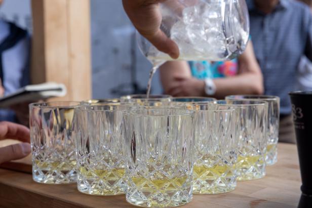 Ein Getränk wird in mehrere Gläser mit Eiswürfeln gegossen.