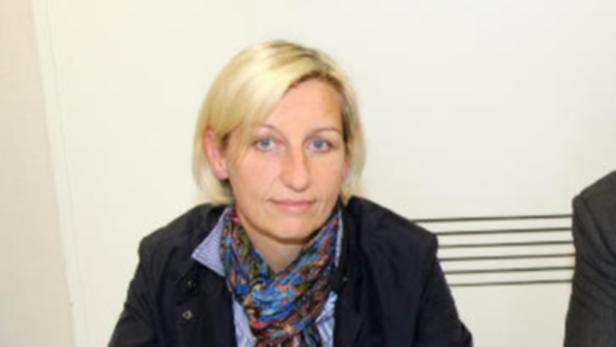 Eine Frau mit blonden Haaren und einem bunten Schal blickt in die Kamera.