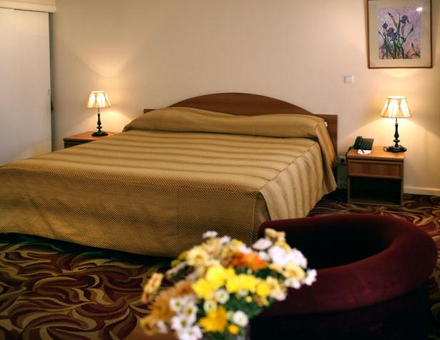 Ein Hotelzimmer mit einem Doppelbett, Nachttischen und einem Blumenstrauß.