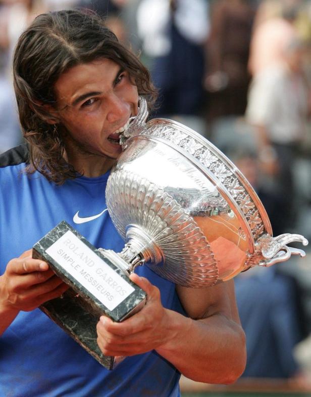 Rafael Nadal beißt in die Trophäe der French Open.