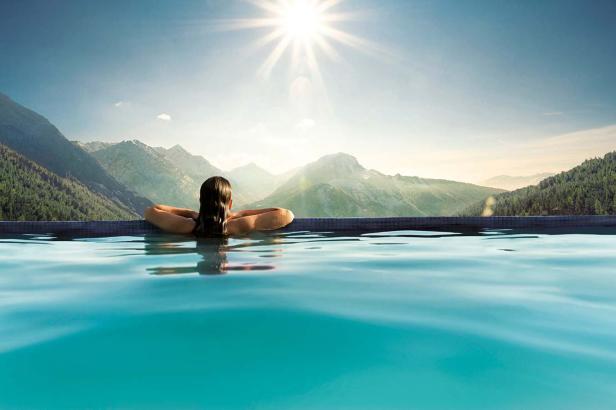 Eine Frau entspannt in einem Pool mit Blick auf eine Berglandschaft.