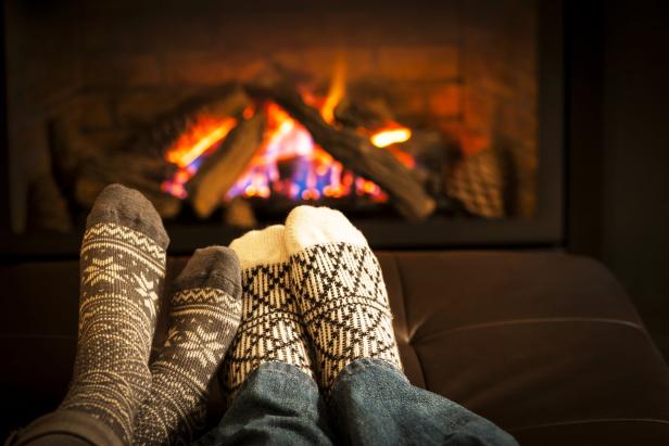 Zwei Paar Füße mit Socken liegen vor einem Kamin.