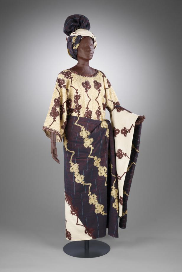 Eine Schaufensterpuppe trägt ein traditionelles afrikanisches Kleidungsstück mit passendem Kopfschmuck.