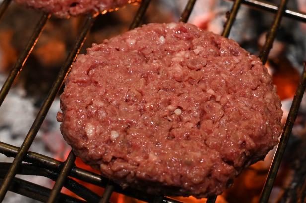 Ein roher Burger liegt auf einem Grill.