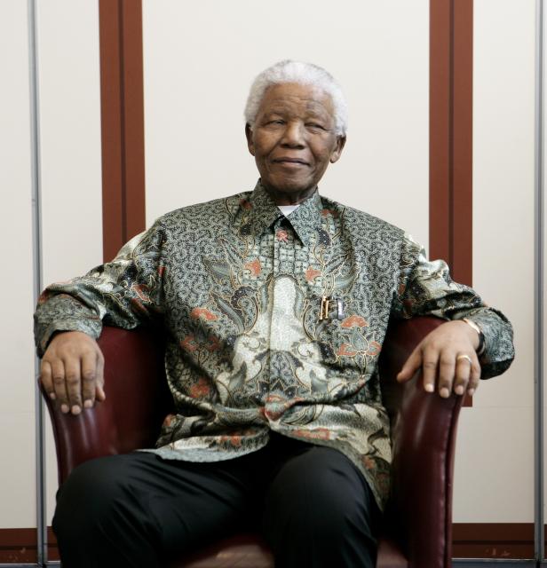 Nelson Mandela sitzt in einem Sessel und lächelt.