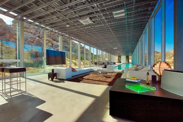 Ein modernes Wohnzimmer mit raumhohen Fenstern und Blick auf eine felsige Landschaft.